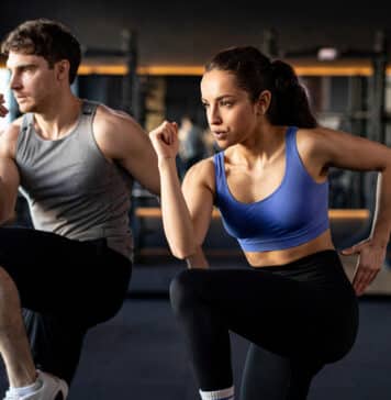Focused sportive couple doing warm up exercises during fitness workout in modern gym